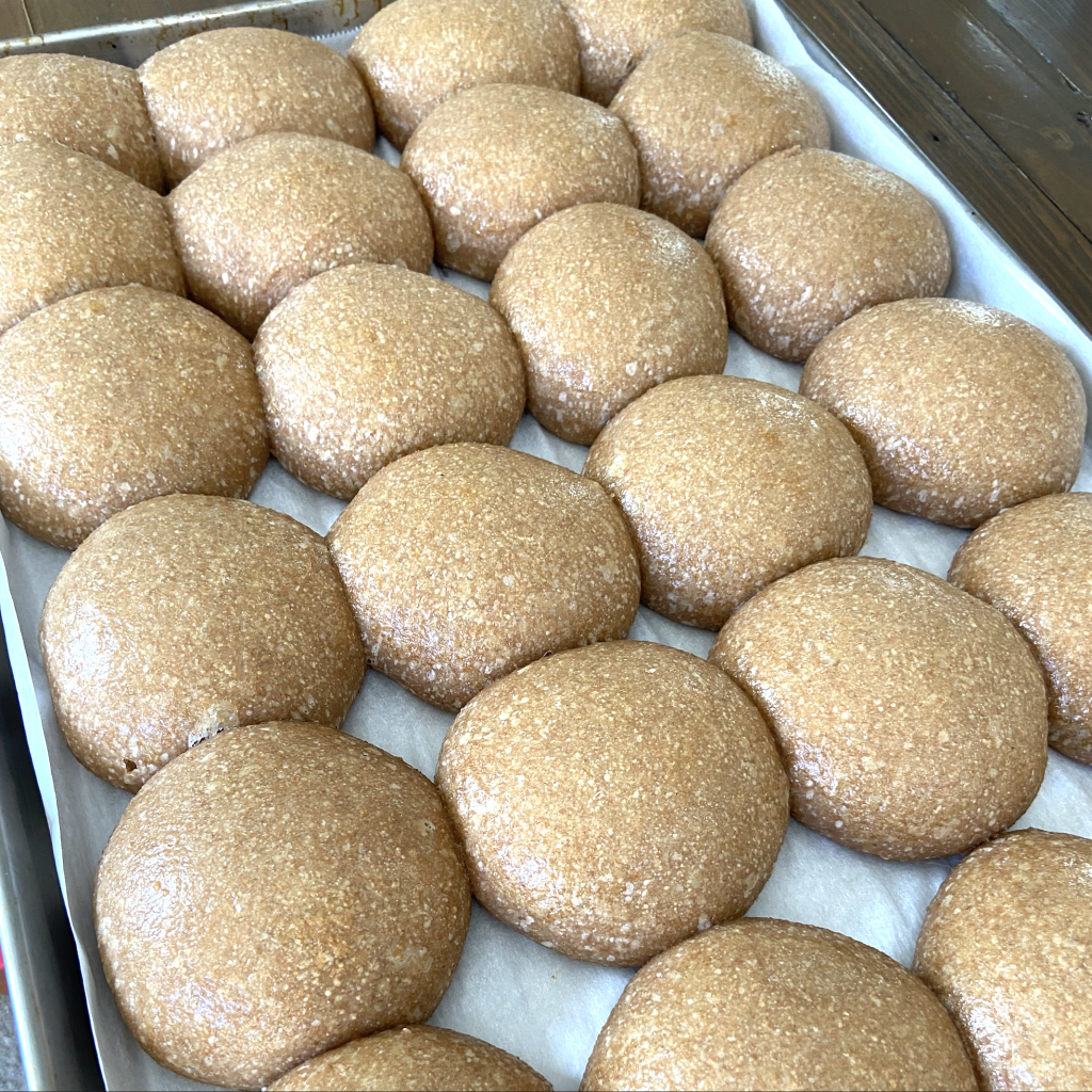 Sourdough buns brushed with butter after being baked.  They are resting on a cookie sheet